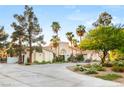 Attractive white home with palm trees and lush landscaping, complete with a circular driveway and fountain at 7185 Ranchito Cir, Las Vegas, NV 89120