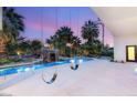Backyard pool and grotto with swings hanging from the patio cover and palm trees, creating a relaxing retreat at 7185 Ranchito Cir, Las Vegas, NV 89120