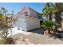 Two-story home showcasing a three-car garage and lush desert landscaping at 7825 Desert Bell Ave, Las Vegas, NV 89128