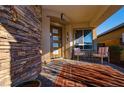 Cozy front porch with brick flooring, adorned with outdoor seating and a decorative stone wall at 9858 Gemstone Sunset Ave, Las Vegas, NV 89148