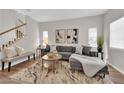 Bright living room with a comfortable gray sofa, stylish coffee table, and staircase with wood and white railings at 11164 African Sunset St, Henderson, NV 89052