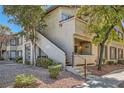 Stucco condo with front porch and access stairs is surrounded by trees and landscaping at 4955 Lindell Rd # 130, Las Vegas, NV 89118