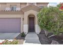 Inviting front entrance with an arched doorway, desert landscaping, and an attached two-car garage at 5655 Danforth Ave, Las Vegas, NV 89141