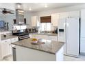 Bright kitchen with white cabinets, granite countertops, a stainless steel range hood, and a center island at 5929 Royal Castle Ln, Las Vegas, NV 89130