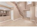 Open-concept living room with high ceilings, staircase, fireplace, and neutral tile flooring at 9740 Floweret Ave, Las Vegas, NV 89117