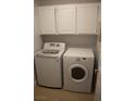 A practical laundry room equipped with a washing machine, a dryer, and convenient overhead storage cabinets at , Las Vegas, NV 89128