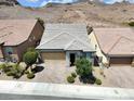 Inviting single-story home with brick-paved driveway and desert landscaping against a backdrop of rolling hills at 1063 Upper Springs St, Henderson, NV 89002