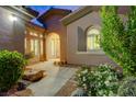 Inviting front entrance with a well-lit arched doorway, desert landscaping, and stone accents at 12 Kennesaw Rd, Henderson, NV 89052