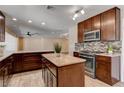 Modern kitchen featuring an island, granite countertops, stainless steel appliances, and tile flooring at 6117 Foxcroft Ave, Las Vegas, NV 89108