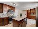Modern kitchen featuring an island, granite countertops, stainless steel appliances, and tile flooring at 6117 Foxcroft Ave, Las Vegas, NV 89108