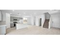 Open-concept floorplan with a well-equipped kitchen, island, and staircase at 77 Tardando Ave, Henderson, NV 89015