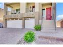 Front entrance featuring a two-car garage, red door, and professionally designed low maintenance landscaping at 9045 Knots Estate St, Las Vegas, NV 89139