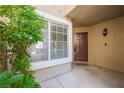 Inviting front porch featuring a brown door, a 'hello' doormat, and adjacent window at 10244 Amber Hue Ln, Las Vegas, NV 89144