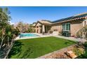 Beautiful backyard with artificial turf, a built-in grill, and a sparkling pool at 10417 Artful Stone Ave, Las Vegas, NV 89149