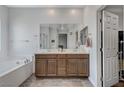 Bright bathroom featuring a double sink vanity, large mirror, soaking tub, and tiled floors at 2796 Sipe Springs St, Las Vegas, NV 89142