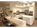 Well-lit kitchen featuring white cabinets, stainless steel appliances, tiled backsplash, large island, and breakfast bar seating at 2809 Winslow Springs Dr, Henderson, NV 89052