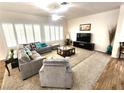Bright living room featuring neutral tones, carpet, large windows with shutters, and a comfortable gray sofa at 2809 Winslow Springs Dr, Henderson, NV 89052