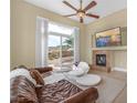 Bright living room with a brown leather sofa, fireplace, and access to the outdoor patio with views at 32 Cerchio Basso, Henderson, NV 89011