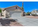 Side view of a home with a two-car garage featuring a concrete driveway and desert landscaping at 444 Flores Cir, Las Vegas, NV 89123