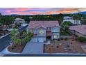 Striking two-story home with a three-car garage and desert landscaping at dusk at 7211 Heggie Ave, Las Vegas, NV 89131