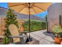 Desert patio with stone pavers, shade umbrella, and comfortable seating at 130 Twin Towers Ave, Las Vegas, NV 89123