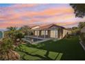 The backyard features a pool, manicured lawn, covered patio, and desert landscaping, perfect for outdoor living at 1343 Panini Dr, Henderson, NV 89052