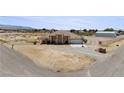 Single-story home with covered porch, desert landscape, and a two-car garage on expansive lot at 2571 N David St, Pahrump, NV 89060