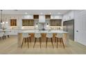 A modern kitchen features an eat-in island with four stools, sleek white cabinetry, and stainless steel appliances at 2621 Spalding Dr, Las Vegas, NV 89134