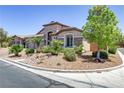 Attractive home exterior with lush landscaping, a three-car garage, and desert rock at 3906 Jacob Lake Cir, Las Vegas, NV 89118