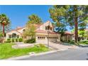 A beautiful home featuring a spacious three-car garage, mature trees, and a well-manicured lawn at 5381 Waving Sage Dr, Las Vegas, NV 89149