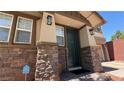 Inviting front entrance with stone accents, a dark green door, and modern sconces at 5627 Spanish Valor Rd, Las Vegas, NV 89135
