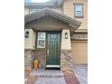 Close-up of front door with a covered porch, stone accents, and lantern sconces at 5627 Spanish Valor Rd, Las Vegas, NV 89135