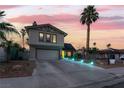 Charming two-story home with a large driveway, well-manicured lawn, and beautiful landscaping at twilight at 7018 Berkshire Pl, Las Vegas, NV 89147