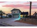 Charming two-story home with a large driveway, well-manicured lawn, and beautiful landscaping at twilight at 7018 Berkshire Pl, Las Vegas, NV 89147