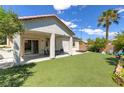 Low-maintenance backyard featuring artificial grass, a covered patio, and desert landscaping at 8232 Silver Vine St, North Las Vegas, NV 89085
