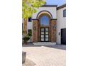 A beautiful front door with stone accents and a lovely arched window above at 9501 Balatta Canyon Ct, Las Vegas, NV 89144
