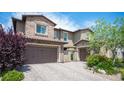 Beautiful home exterior featuring brick accents, a paved driveway, a gated courtyard, and a two-car garage at 12018 Vento Forte Ave, Las Vegas, NV 89138