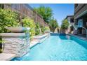 Backyard pool area features a rock waterfall feature, lush landscaping and basketball hoop at 12018 Vento Forte Ave, Las Vegas, NV 89138