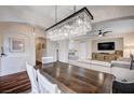 Open dining room with contemporary chandelier, wood floors, and access to the living room and kitchen at 167 Thunder Plains Way, Henderson, NV 89012
