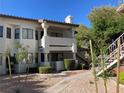 Inviting condo exterior showcasing a stucco finish, well-manicured shrubs, and an exterior staircase leading to the upper units at 2704 Otter Creek Ct # 101, Las Vegas, NV 89117