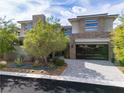 Contemporary two-story home boasting a stone accent wall and a sleek, glass-paneled garage door at 5 Moonfire Dr, Las Vegas, NV 89135
