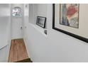 Bright hallway with hardwood floors, a white door, and framed art on the white walls at 5221 Tropical Peach Dr, Las Vegas, NV 89118