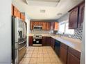 The kitchen features stainless steel appliances, including a refrigerator and oven, along with wooden cabinets and tile floors at 6215 Don Zarembo Ave, Las Vegas, NV 89108