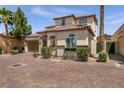 Beautiful two-story house featuring a tile roof, lush landscaping, and a brick driveway at 63 Via Di Mello, Henderson, NV 89011