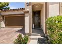 Inviting front entrance featuring a dark wood door, brick driveway, and lovely landscaping at 63 Via Di Mello, Henderson, NV 89011