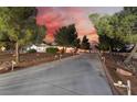 Beautiful single story home with a long driveway, landscaped yard, and charming exterior lighting at dusk at 6931 Leon Ave, Las Vegas, NV 89131