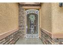 Charming front entrance with decorative wrought iron gate, stone accents, and textured stucco walls at 7497 Alamo Ranch Ave, Las Vegas, NV 89179