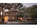 Elegant two-story home with manicured lawn and mature trees at twilight at 1413 Iron Hills Ln, Las Vegas, NV 89134
