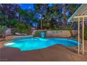 Inviting backyard pool featuring a basketball hoop, lounge chairs and lush tropical landscaping illuminated at twilight at 2231 Marlboro Dr, Henderson, NV 89014