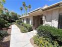 Home's front entrance with security door, desert landscaping, and mature trees in a park-like setting at 2480 Domingo St, Las Vegas, NV 89121
